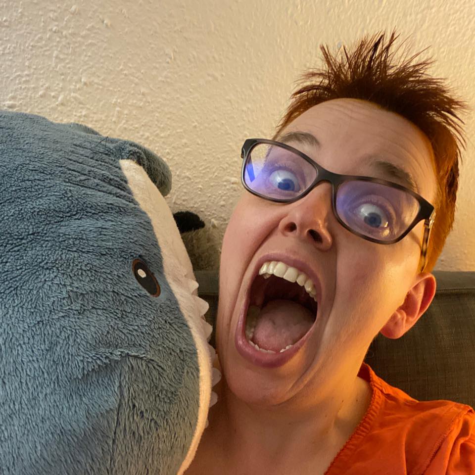 Schreiende Autorin wird von gigantischem Plüsch-Hai angefallen. Großaufnahme.