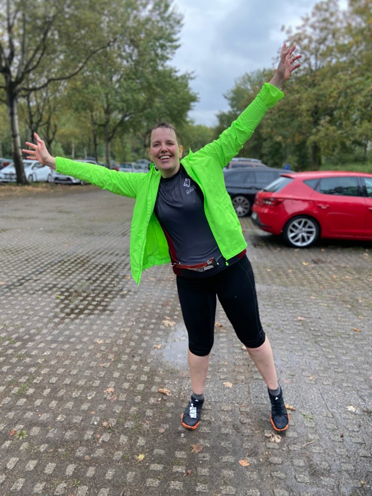 Klatschnasse Läuferin in neongrüner (neongelber? Darüber streiten wir zuhause) Regenjacke jubelt auf den Parkplatz. Alles ist nass. Wirklich alles.