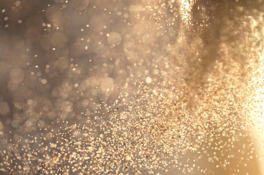 Eine Wolke goldglänzenden Glitters in warmem Licht.