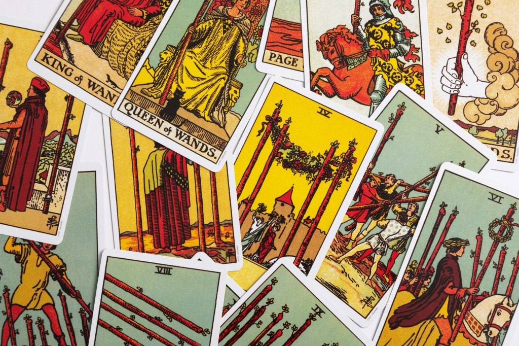 Großaufnahme mehrerer bunter Tarotkarten, die durcheinander mit der Bildseite nach oben auf einer hellen Fläche liegen (Rider-Waite-Tarot).