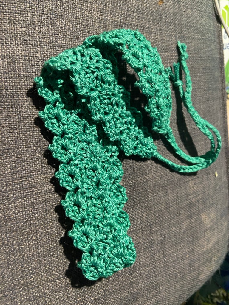 Häkelwerk 2: Ein meergrünes Stirnband auf grauem Sofa.