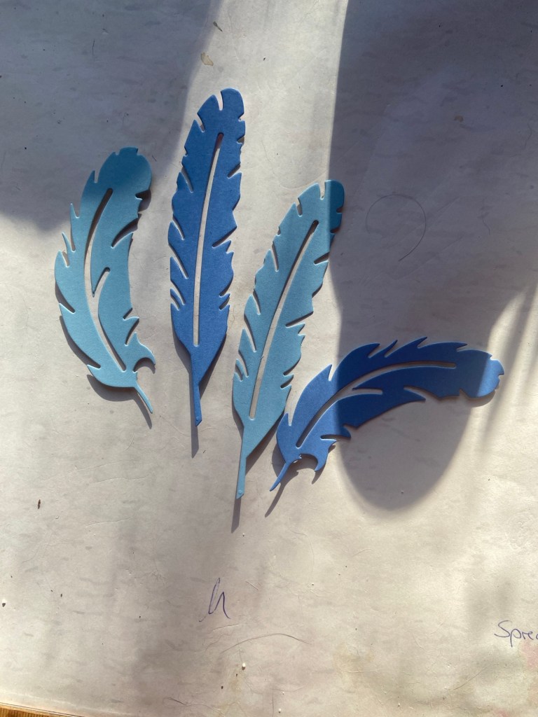 Vier blaue Papierfedern.