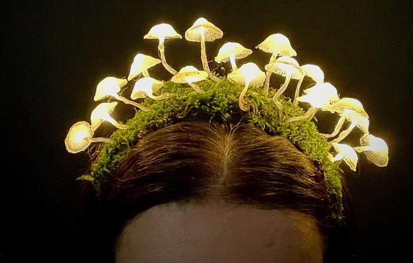 Ein Diadem aus künstlichem Moos, auf dem leuchtende Pilze wachsen.